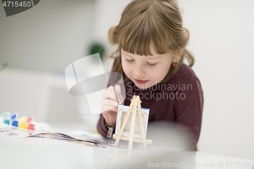 Image of little girl painting on canvas