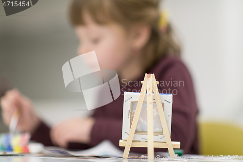 Image of little girl painting on canvas