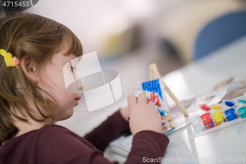 Image of little girl painting on canvas