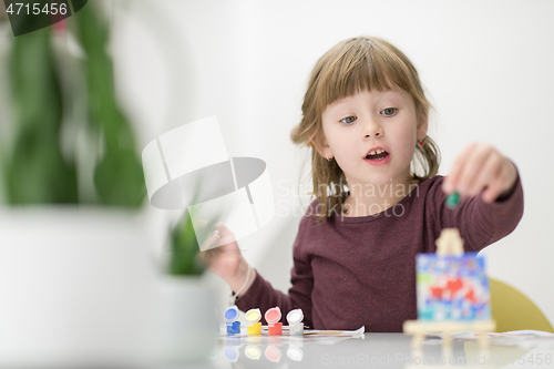 Image of little girl painting on canvas