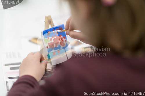 Image of little girl painting on canvas