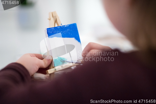 Image of little girl painting on canvas