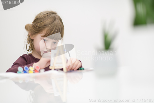 Image of little girl painting on canvas