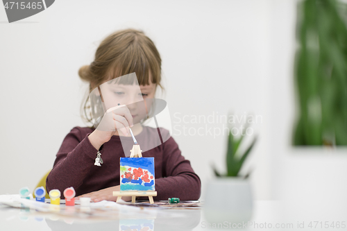 Image of little girl painting on canvas