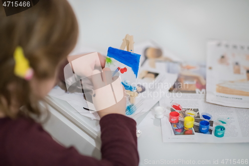 Image of little girl painting on canvas