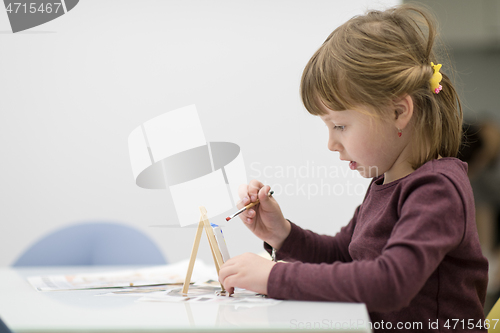 Image of little girl painting on canvas