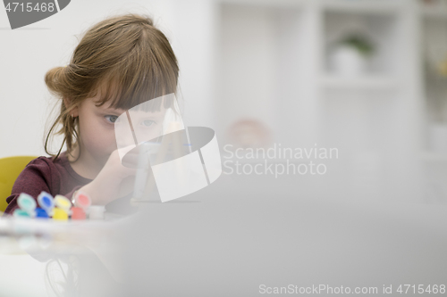 Image of little girl painting on canvas