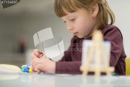 Image of little girl painting on canvas