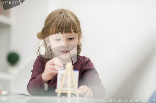 Image of little girl painting on canvas