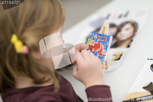 Image of little girl painting on canvas