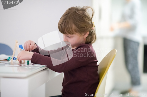 Image of little girl painting on canvas