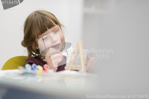 Image of little girl painting on canvas