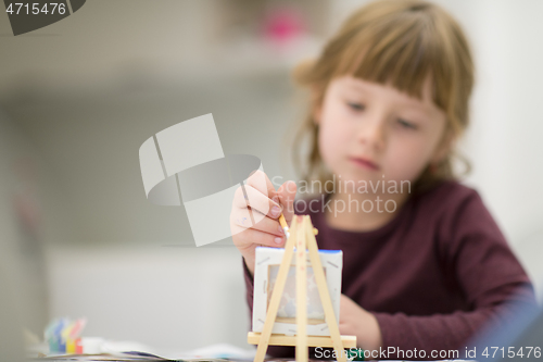 Image of little girl painting on canvas