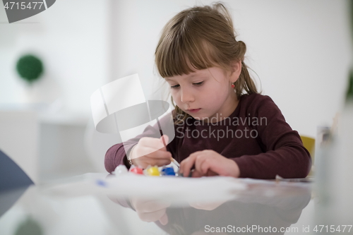 Image of little girl painting on canvas