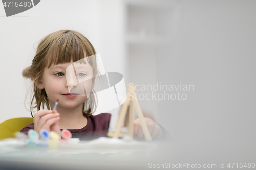 Image of little girl painting on canvas