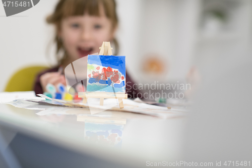 Image of little girl painting on canvas