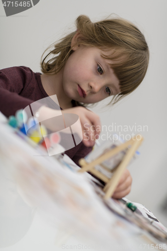 Image of little girl painting on canvas