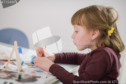 Image of little girl painting on canvas