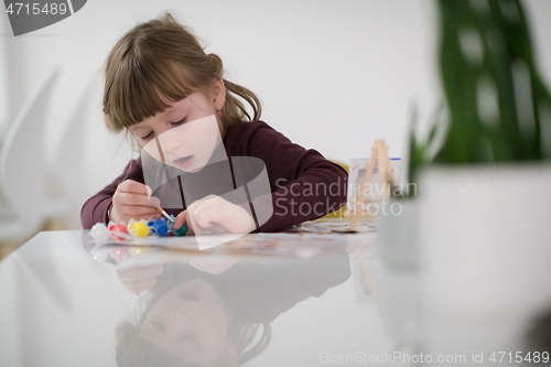 Image of little girl painting on canvas