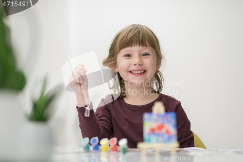 Image of little girl painting on canvas