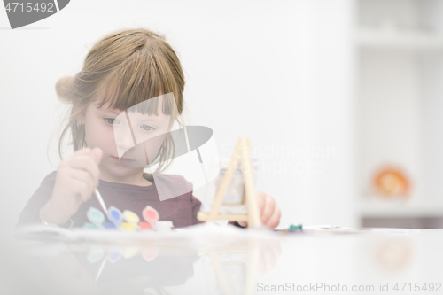 Image of little girl painting on canvas