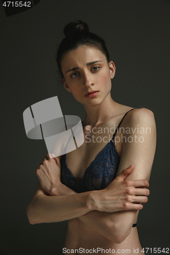 Image of Half-length portrait of young sad woman on dark studio background