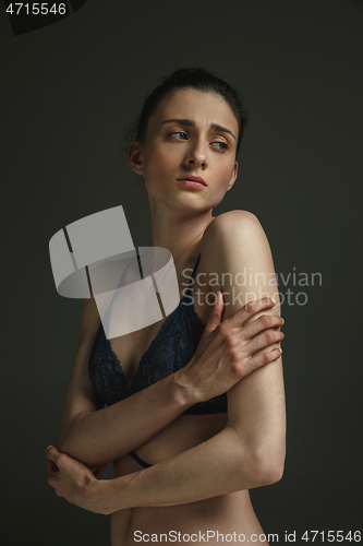 Image of Half-length portrait of young sad woman on dark studio background