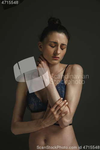 Image of Half-length portrait of young sad woman on dark studio background