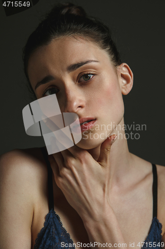 Image of Half-length portrait of young sad woman on dark studio background