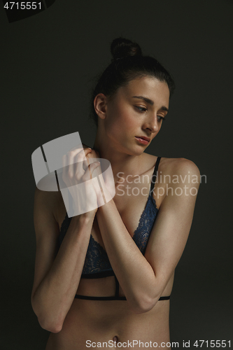 Image of Half-length portrait of young sad woman on dark studio background