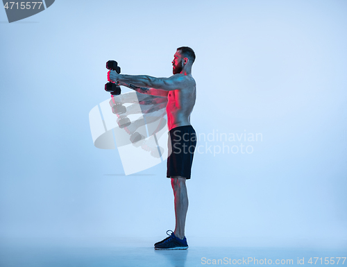 Image of Young caucasian bodybuilder training over blue background