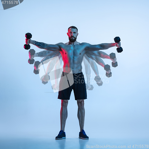 Image of Young caucasian bodybuilder training over blue background