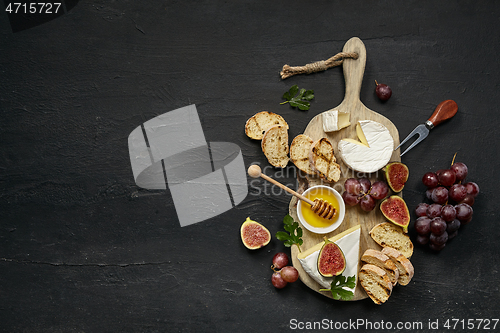 Image of Two glasses of red wine and cheese plate with fruit on the black stone