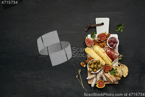 Image of Top view of tasty cheese plate with the fruit on the black stone