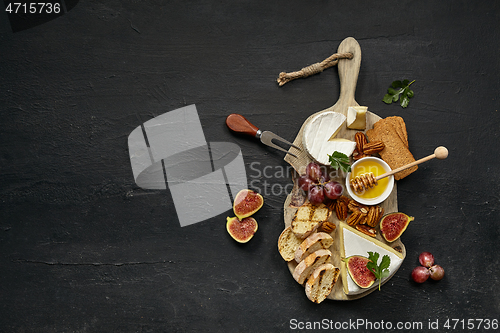 Image of Two glasses of red wine and cheese plate with fruit on the black stone