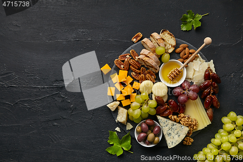 Image of Top view of tasty cheese plate with fruit on the black stone