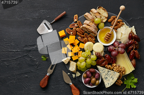 Image of Top view of tasty cheese plate with fruit on the black stone