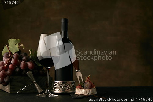 Image of Front view of tasty fruit plate with the wine bottle on dark studio background