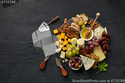 Image of Top view of tasty cheese plate with fruit on the black stone