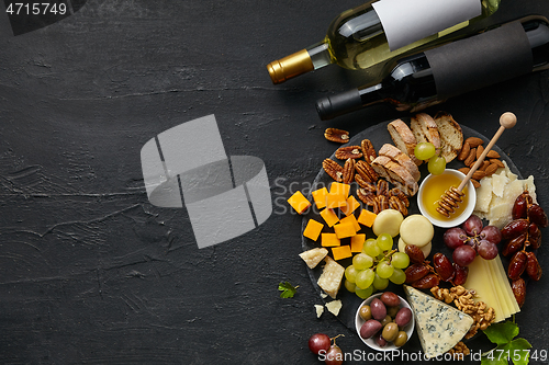 Image of Top view of tasty cheese plate with fruit on the black stone