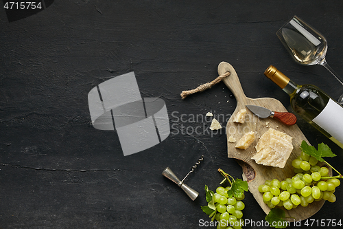 Image of Two glasses of white wine and a tasty cheese plate on a wooden kitchen plate.