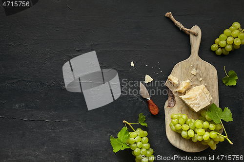 Image of Top view of tasty cheese plate with the fruit on the black stone