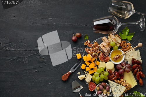 Image of Top view of tasty cheese plate with fruit on the black stone