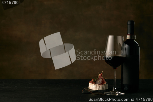 Image of Front view of tasty fruit plate with the wine bottle on dark studio background