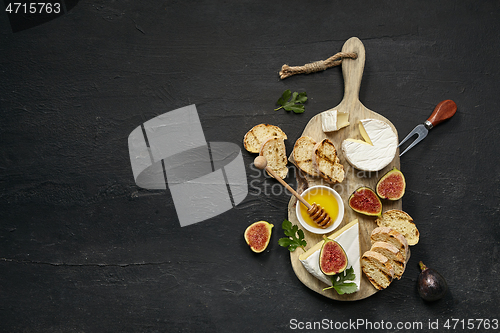 Image of Two glasses of red wine and cheese plate with fruit on the black stone