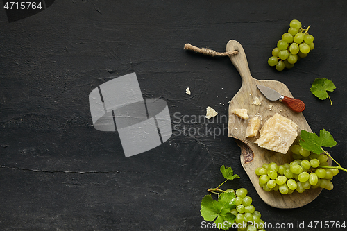 Image of Top view of tasty cheese plate with the fruit on the black stone