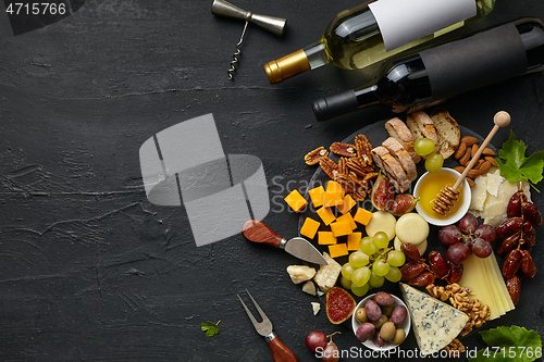 Image of Top view of tasty cheese plate with fruit on the black stone