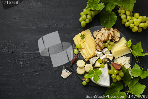 Image of Top view of tasty cheese plate with fruit on the black stone