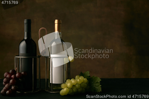 Image of Front view of tasty fruit plate with the wine bottles on dark studio background