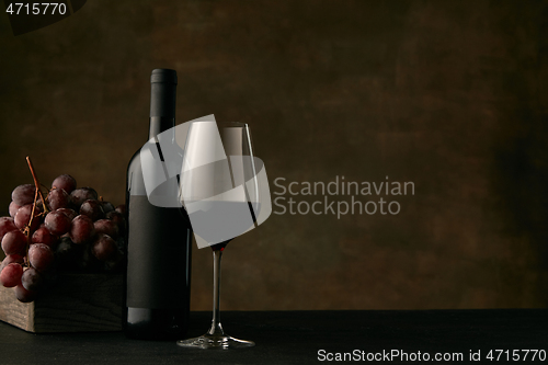 Image of Front view of tasty fruit plate with the wine bottle on dark studio background